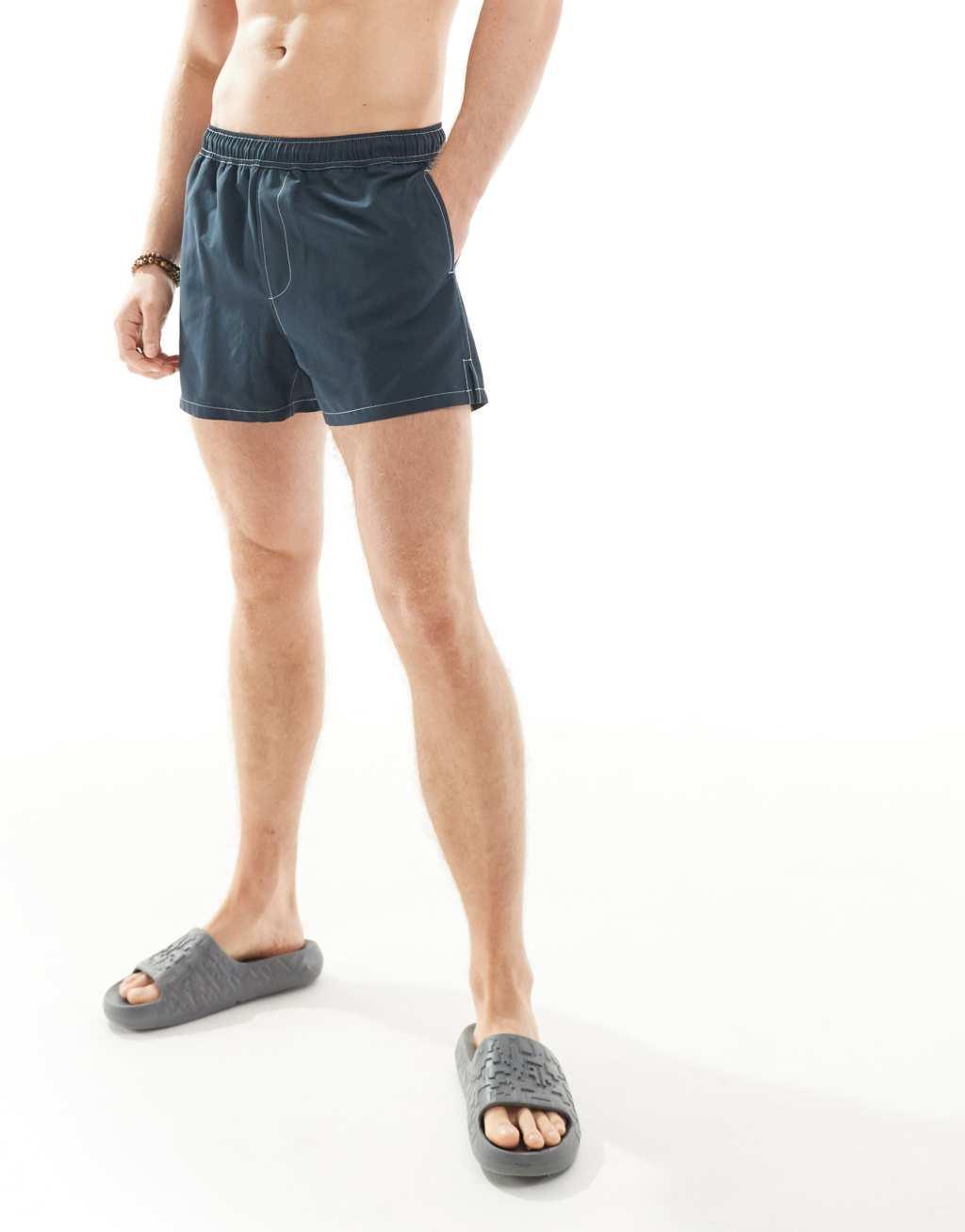 ASOS DESIGN swim shorts in short length with contrast stitch detail in navy Product Image