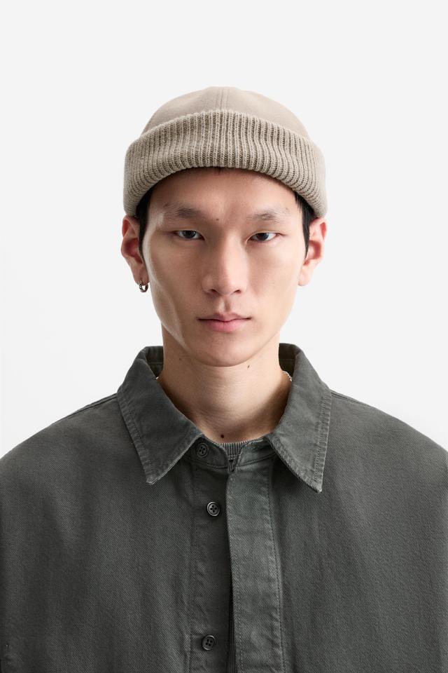 Hat made of tonal matching fabrics with turned-up knit brim. Adjusts with loop. Product Image