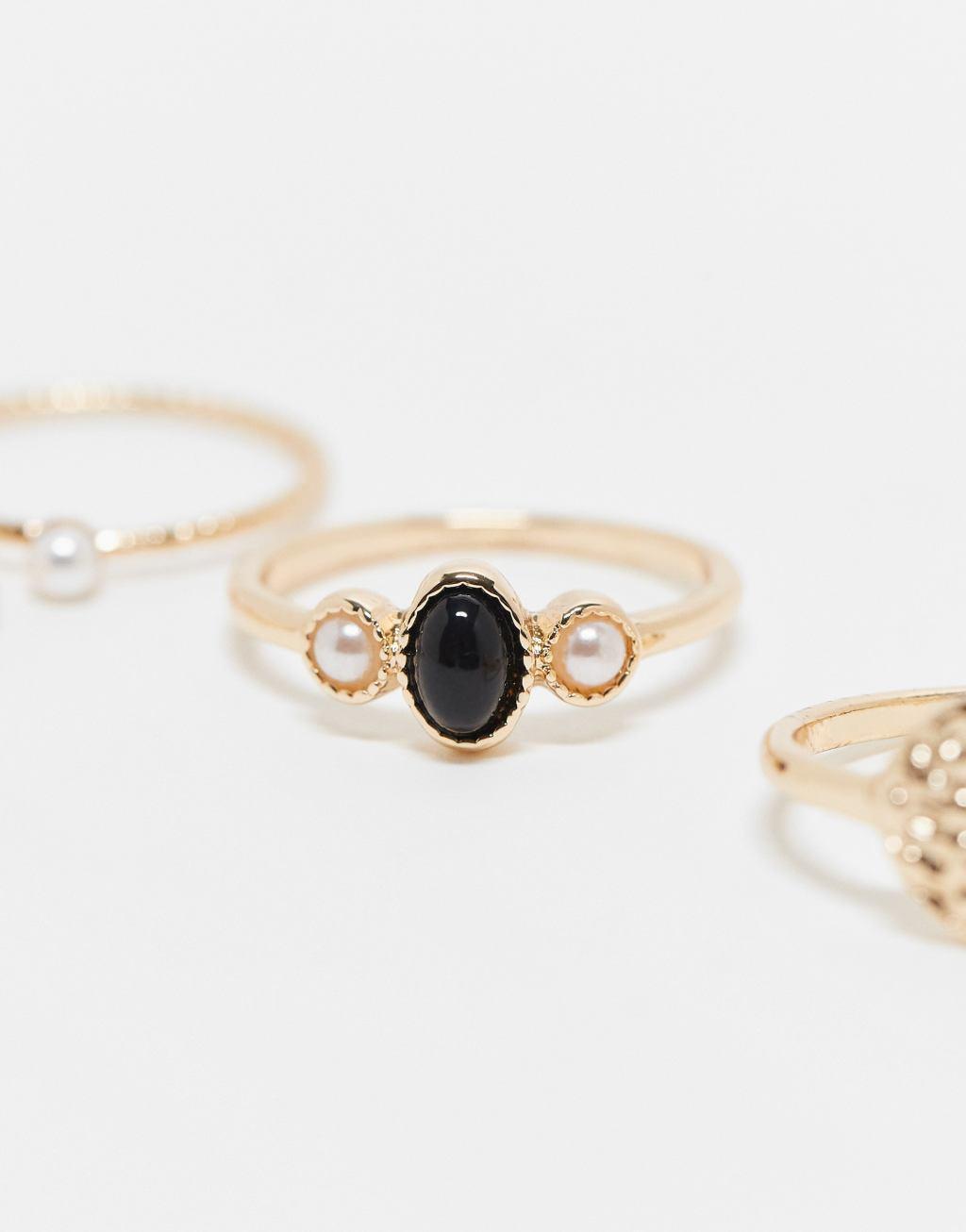 ASOS DESIGN 5-pack rings with black stone and faux pearl design in gold tone Product Image