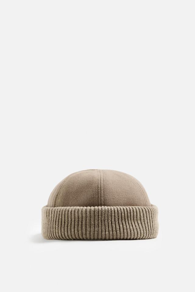 Hat made of tonal matching fabrics with turned-up knit brim. Adjusts with loop. Product Image