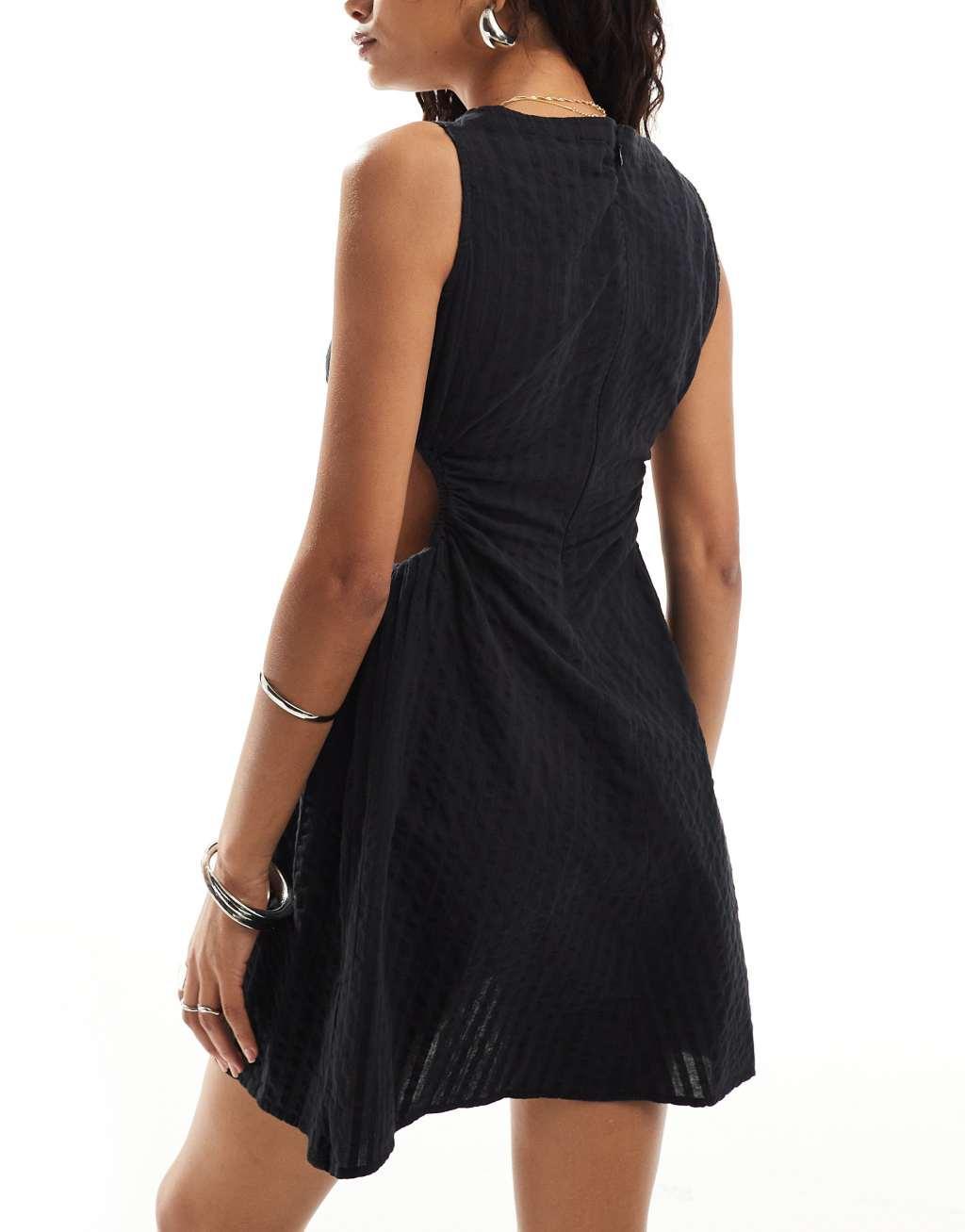 Monki sleeveless mini seersucker dress with ruched sides and cut out detail in black Product Image